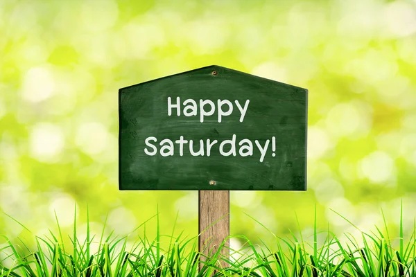 Green sign board with natural background and message Happy saturday — Stock Photo, Image