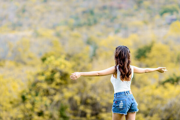 Carefree happy woman in spring or summer forest park raising arm