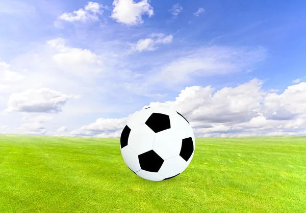 Pelota de fútbol en el campo verde con cielo azul — Foto de Stock