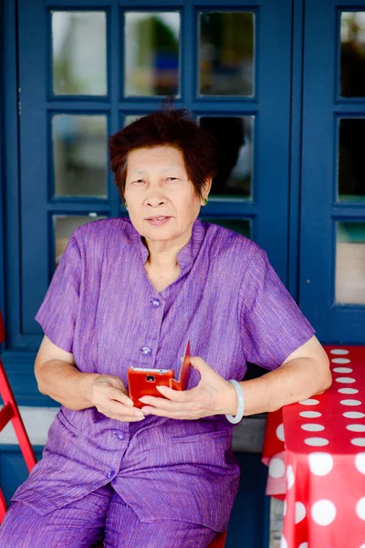 Senior vrouw met behulp van haar smartphone om te bellen in een restaurant — Stockfoto