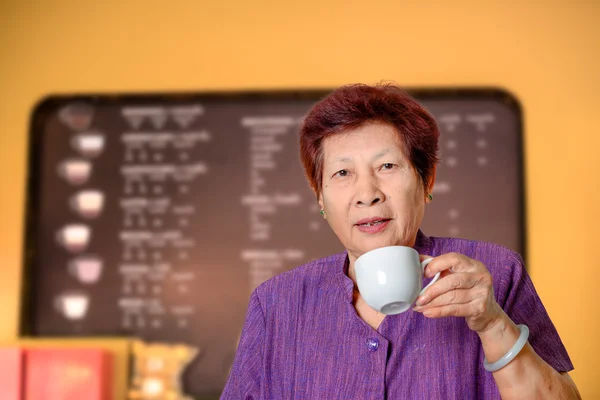 Asiática senior mujer disfrutando de taza de té en café tienda . — Foto de Stock