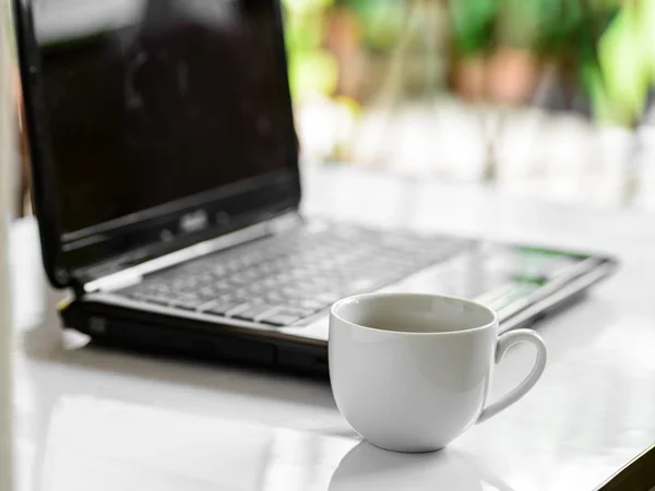 Šálek kávy a laptop pro podnikání, selektivní zaměřují na kávu. — Stock fotografie