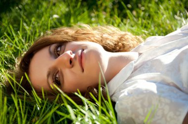 Kızıl saçlı kadın güneşli bir gün çim üzerinde yalan