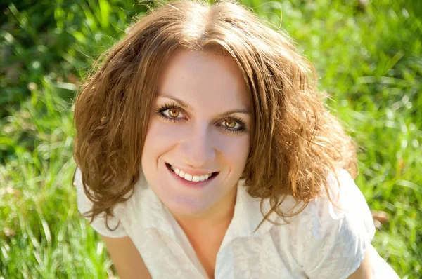 Red-haired woman sitting on the  grass and smiling at sunny day — Stock Photo, Image