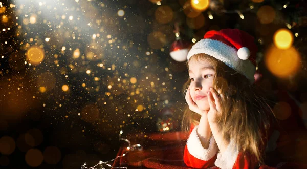 Noel Baba şapkalı ve Noel ağacının altındaki kırmızı elbiseli küçük kız hayal kuruyor, bayramı bekliyor, ekose bir battaniyenin üzerinde yatıyor. Kağıt üzerinde bir mektup, hediyeler. Yeni yıl, Noel. Işıkları söndür