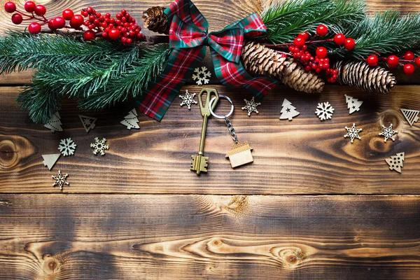 Anahtar zincirli ev anahtarı, neşeli bir çevre dostu, Noel ağacıyla doğal bir arka plan. Mutlu yıllar, hediye, tebrik kartı. Satın alma, inşaat, taşınma, ipotek