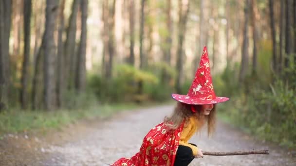 Dziewczyna Kostiumie Czarownicy Kapeluszu Miotle Bawi Się Jesiennym Lesie Idąc — Wideo stockowe