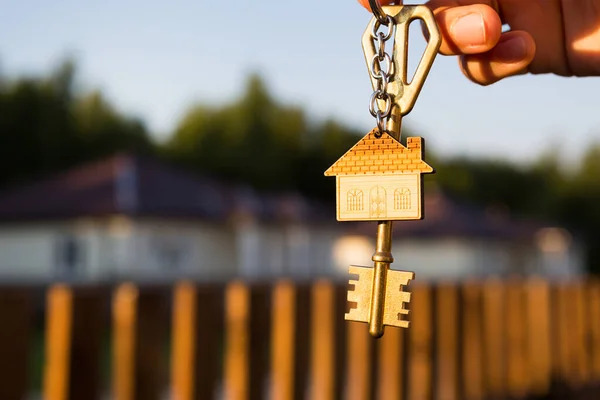 Schlüsselanhänger Mit Schlüsselanhänger Der Hand Hintergrund Von Zaun Und Hütte — Stockfoto