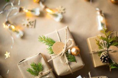 Noel ve yeni yıl hediyelerini çevre dostu malzemelerle paketleyin: kraft kağıdı, köknar dalları, koniler, sicim. Sahte etiketler, doğal dekor, el yapımı, DIY. Şenlik havası. Düz, arka plan