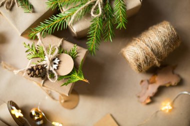 Noel ve yeni yıl hediyelerini çevre dostu malzemelerle paketleyin: kraft kağıdı, köknar dalları, koniler, sicim. Sahte etiketler, doğal dekor, el yapımı, DIY. Şenlik havası. Düz, arka plan