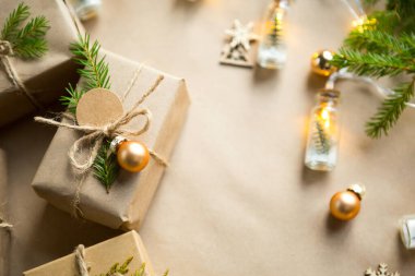 Noel ve yeni yıl hediyelerini çevre dostu malzemelerle paketleyin: kraft kağıdı, köknar dalları, koniler, sicim. Sahte etiketler, doğal dekor, el yapımı, DIY. Şenlik havası. Düz, arka plan