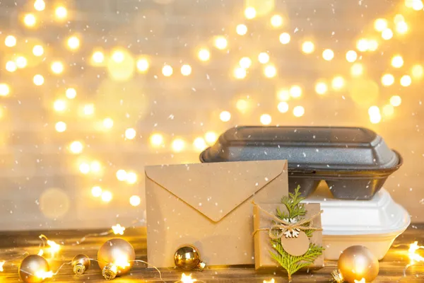 食品配送サービスコンテナのクリスマスの装飾 大晦日のプロモーション 既製のホット注文 テーブルの上に妖精の光の中で使い捨てプラスチック製の箱 祝日のケータリングの仕事 コピースペース モックアップ — ストック写真