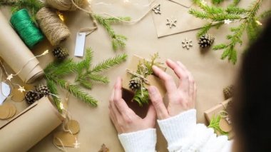 Eller Noel ve yeni yıl hediyelerini çevre dostu malzemelerle paketliyor: Kraft kağıdı, canlı köknar dalları, koniler, sicim, yayla bağlanmış. Sahte etiketler, doğal dekor, el yapımı, düz. Şenlik havası