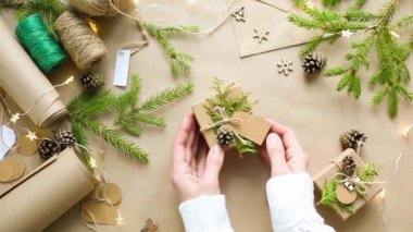 Eller Noel ve yeni yıl hediyelerini çevre dostu malzemelerle paketliyor: Kraft kağıdı, canlı köknar dalları, koniler, sicim, yayla bağlanmış. Sahte etiketler, doğal dekor, el yapımı, düz. Şenlik havası