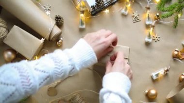 Eller Noel ve yeni yıl hediyelerini çevre dostu malzemelerle paketliyor: Kraft kağıdı, canlı köknar dalları, koniler, sicim, yayla bağlanmış. Sahte etiketler, doğal dekor, el yapımı, düz. Şenlik havası