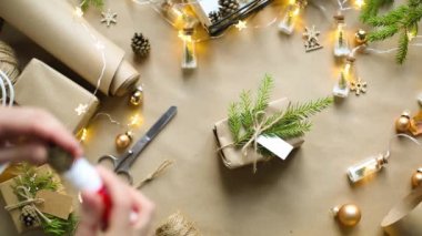 Eller Noel ve yeni yıl hediyelerini çevre dostu malzemelerle paketliyor: Kraft kağıdı, canlı köknar dalları, koniler, sicim, yayla bağlanmış. Sahte etiketler, doğal dekor, el yapımı, düz. Şenlik havası