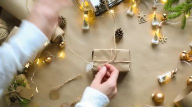 Eller Noel ve yeni yıl hediyelerini çevre dostu malzemelerle paketliyor: Kraft kağıdı, canlı köknar dalları, koniler, sicim, yayla bağlanmış. Sahte etiketler, doğal dekor, el yapımı, düz. Şenlik havası
