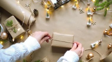Eller Noel ve yeni yıl hediyelerini çevre dostu malzemelerle paketliyor: Kraft kağıdı, canlı köknar dalları, koniler, sicim, yayla bağlanmış. Sahte etiketler, doğal dekor, el yapımı, düz. Şenlik havası