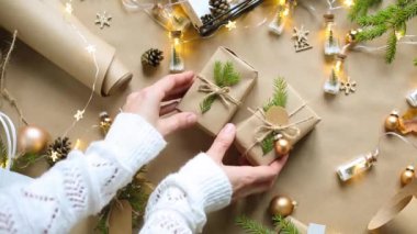Eller Noel ve yeni yıl hediyelerini çevre dostu malzemelerle paketliyor: Kraft kağıdı, canlı köknar dalları, koniler, sicim, yayla bağlanmış. Sahte etiketler, doğal dekor, el yapımı, düz. Şenlik havası