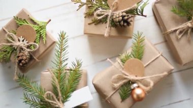 Noel ve yeni yıl için hediye kutusunu çevre dostu malzemelerle döndür: kraft kağıdı, köknar dalları, koniler, sicim. Sahte etiketler, doğal dekor, el yapımı, DIY. Düz, arka plan, Minimalizm
