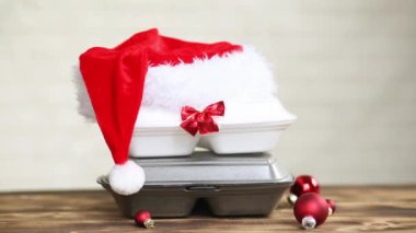 Yemek dağıtım konteynırlarının Noel dekoru. Yılbaşı gecesi terfisi. Sipariş hazır, tek kullanımlık plastik kutu masanın üzerinde. Bayramlarda yemek şirketinde çalışıyorum. Noel Baba şapkası, kırmızı top