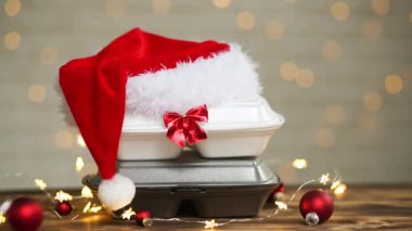 Yemek dağıtım konteynırlarının Noel dekoru. Yılbaşı gecesi terfisi. Sipariş hazır, tek kullanımlık plastik kutu masanın üzerinde. Bayramlarda yemek şirketinde çalışıyorum. Noel Baba şapkası, kırmızı top