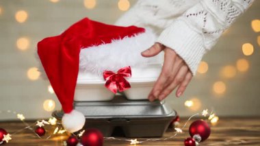 Yemek dağıtım konteynırlarının Noel dekoru. Yılbaşı gecesi terfisi. Elle alınır ve tek kullanımlık plastik kutudan sipariş verilir. Bayramlarda yemek şirketinde çalışıyorum. Noel Baba şapkası, kırmızı top