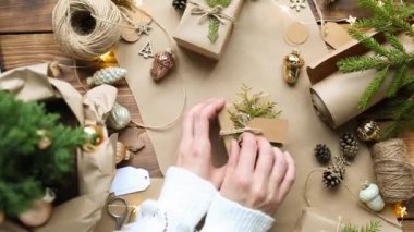 Eller Noel ve yeni yıl hediyelerini çevre dostu malzemelerle paketliyor: Kraft kağıdı, canlı köknar dalları, koniler, sicim, yayla bağlanmış. Sahte etiketler, doğal dekor, el yapımı, düz. Şenlik havası