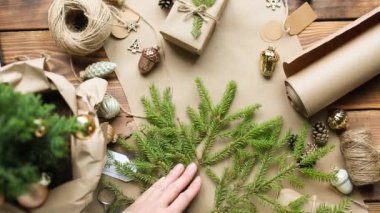 Eller Noel ve yeni yıl hediyelerini çevre dostu malzemelerle paketliyor: Kraft kağıdı, canlı köknar dalları, koniler, sicim, yayla bağlanmış. Sahte etiketler, doğal dekor, el yapımı, düz. Şenlik havası