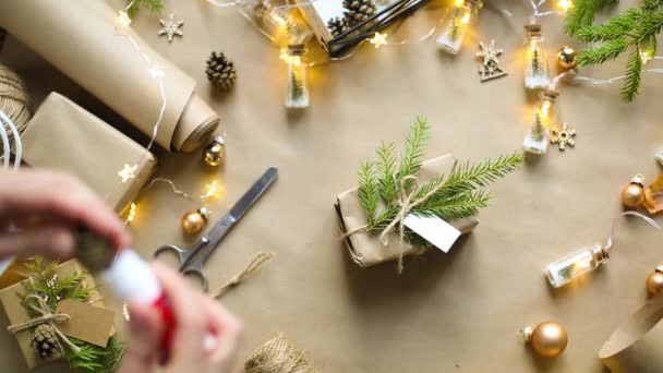 手把圣诞礼物和新年礼物打包成环保材料 牛皮纸 活枞树枝条 用弓子捆扎 带有模型的标签 天然装饰 手工制作 节日气氛 — 图库视频影像