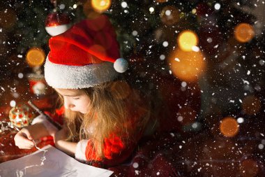 Noel Baba şapkalı ve Noel ağacının altındaki kırmızı elbiseli küçük kız hayal kuruyor, bayramı bekliyor, ekose bir battaniyenin üzerinde yatıyor. Kağıt üzerinde bir mektup, hediyeler. Yeni yıl, Noel. Işıkları söndür
