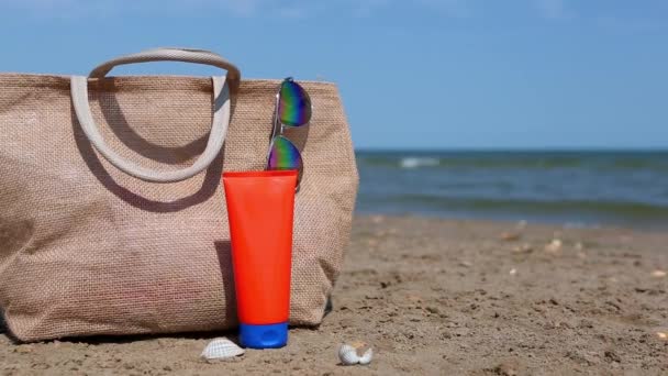 Egy Narancssárga Cső Naptejjel Napszemüveggel Egy Strandtáska Állvánnyal Homokon Tenger — Stock videók