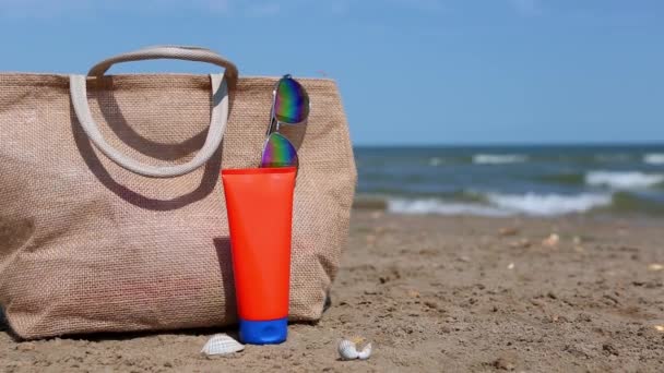 Egy Narancssárga Cső Naptejjel Napszemüveggel Egy Strandtáska Állvánnyal Homokon Tenger — Stock videók