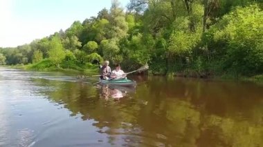 Family kayak trip. An elderly married couple with a grandson rowing a boat on the river, a water hike, a summer adventure. Tourism, active old age. Russia, Kaluga, summer 2021