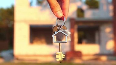 Müstakbel evin anahtarı bir inşaat alanının arka planında ve gözenekli beton bloktan duvarlarda. Bir ev inşa etmek, yeni bir kulübeye taşınmak, kırsalda bir çiftlik.