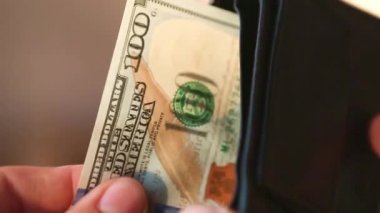 El, 100 dolarlık banknotu yığının içine koyar ve bir banknot alır. Nakit para, 100 dolarlık banknotlar. Finans, ekonomi, mali planlama, ekonomi, tasarruflar.