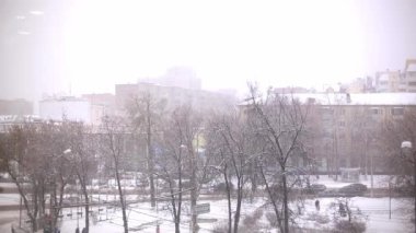 A snowstorm in the city, a view from the window from a height of trees, people, cars driving on the road. Kaluga, Russia, January 6, 2022