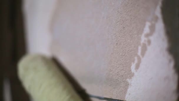 建設ローラーをコーティングする液体プライマーを適用すると 多孔質ブロックで作られた家の壁を完了するための準備です 塗装のためのプライマー 乾燥した建物の混合物で治療 — ストック動画