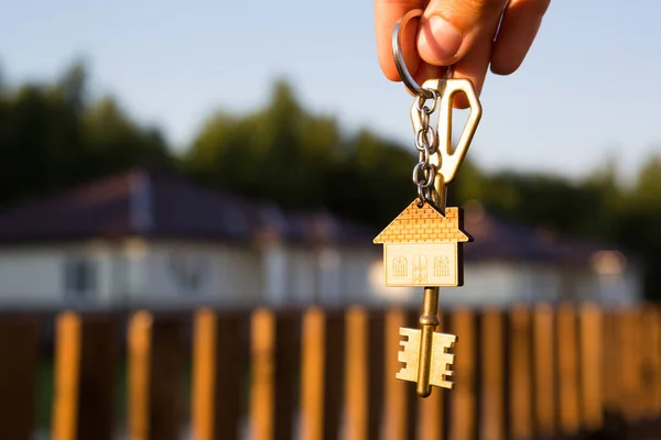 Schlüsselanhänger Mit Schlüsselanhänger Der Hand Hintergrund Von Zaun Und Hütte — Stockfoto