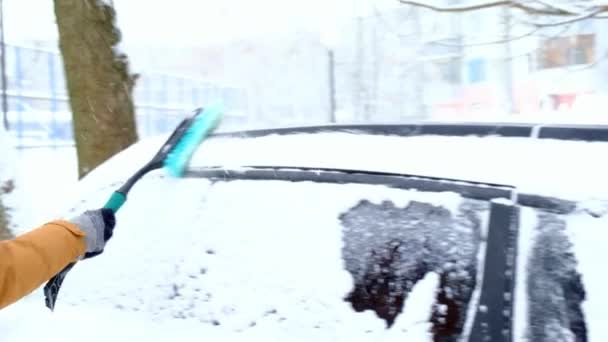 一场大雪过后 一个人把雪从汽车上刷了下来 一只手在一个芥末夹克与汽车扫帚在白色的身体 冬季气候条件 慢动作 — 图库视频影像