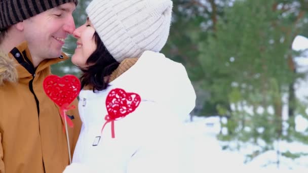 心の形をした赤い装飾が施された雪の中で 冬の屋外のデートを愛する男性と女性 バレンタインデー 散歩中の愛の幸せなカップル 抱擁とキス — ストック動画