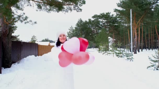 幸せな女性は雪と冬にハート型の風船を屋外に投げます バレンタインデー 愛と愛情 ボーイフレンドからの贈り物 愛の宣言 ライフスタイル スローモーションビデオ4K — ストック動画