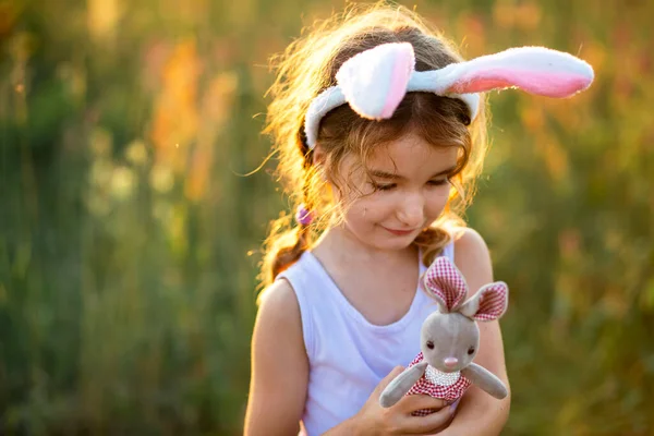 Милая Летняя Девочка Кроличьими Ушами Нежно Обнимает Игрушечного Кролика Природе — стоковое фото