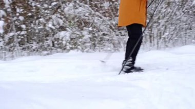 Kayakçı, kar yağışlı ormanda elinde kayak sopalarıyla şapka içinde kayak yapıyor. Kır ormanlarında kayak yapmak, açık hava sporları, sağlıklı yaşam tarzı. Yavaş çekim 4k video