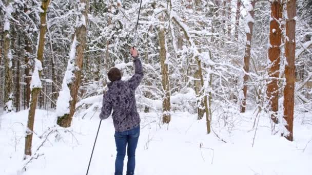 Narciarz Kapeluszu Pomponem Kijkami Narciarskimi Ręku Śnieżnym Lesie Śniegiem Narciarstwo — Wideo stockowe