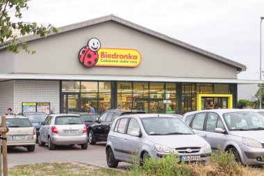 POLAND, BYDGOSZCZ - 27 Mayıs 2019: Logo Biedronka. Polonya 'daki en büyük indirimli süpermarket zinciri Portekizli Jeronimo Martins' e ait. Mağaza önü, arabalar ve alışveriş sonrası insanlar.