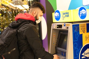 POLAND, TORUN - 5 Aralık 2020: adam ATM yakınlarında para çekti. Adam krediyi para için kullanıyor. 