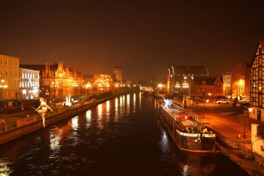 POLAND, BYDGOSZCZ Mai 3, 2020: Brda Nehri üzerinde ip cambazı heykeli olan bir köprüden görünen şehir manzarası. Güneşli bir bahar gününde eski kasaba mimarisi
