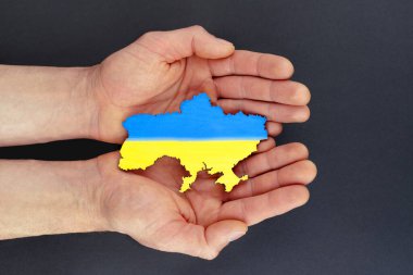 Erkek ellerinin üst görüntüsü Ukrayna haritasını siyah arka planda tutuyor. Kavram