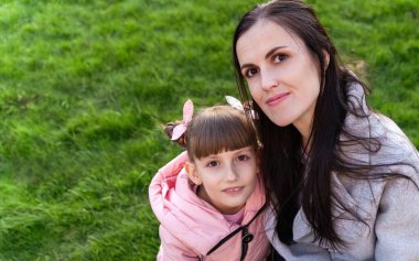 Anne ve kızı baharda. Yeşil çimlerde yaşayan genç bir kadın ve küçük bir kız. Anneler günü, kızlar günü. Aile